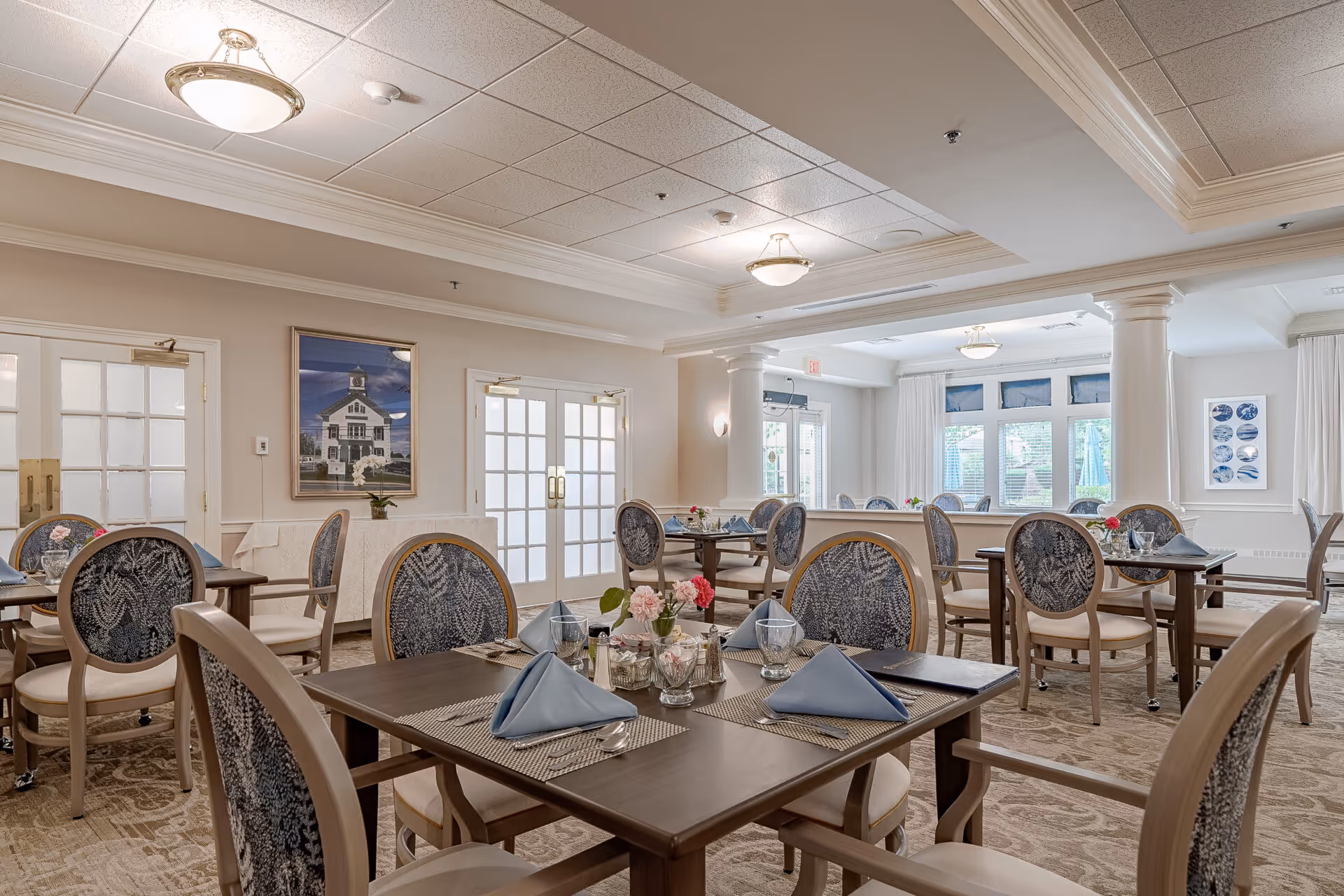 Elegant communal dining room with set tables, upholstered chairs, folded napkins, and soft lighting.
