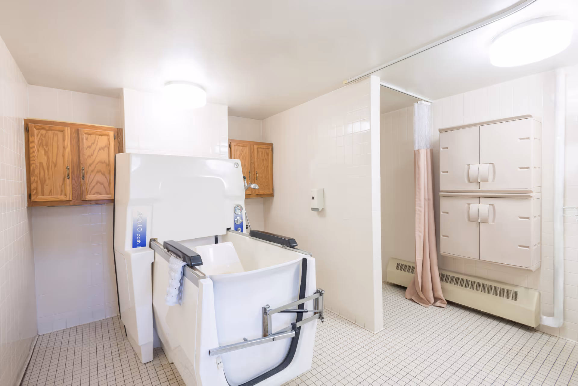Institutional bathroom with a large walk-in assisted tub, tiled floor, wooden cabinets, wall storage and a shower stall with a curtain.