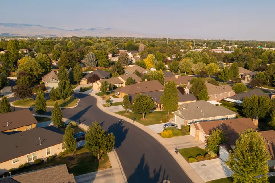 Aerial view of a tree-lined suburban neighborhood with single-story houses and curving streets.