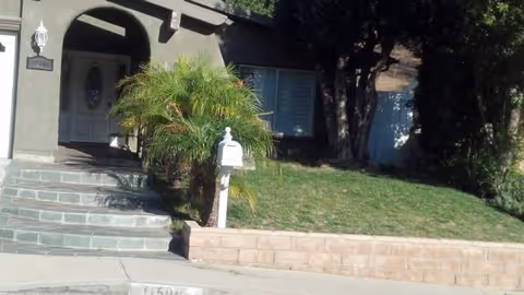 Front entrance of Zann Daily Care senior living facility with steps, a palm plant, and mailbox.