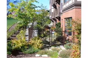 Brick retirement estate exterior with stairs, railing, and lush garden landscaping.