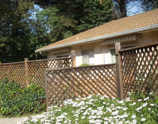 Exterior view of Bel Amor facility with lattice fence and white flowers.