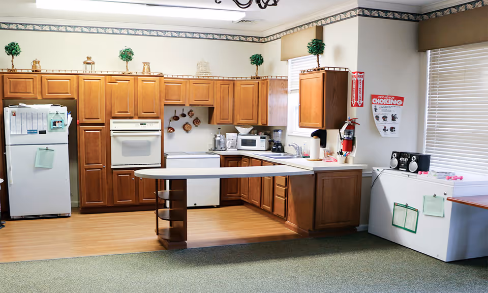 A spacious kitchen with wooden cabinets, white appliances, a peninsula counter, and a refrigerator and microwave.