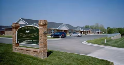 Exterior view of Warrensburg Senior Housing with a brick sign and curved driveway