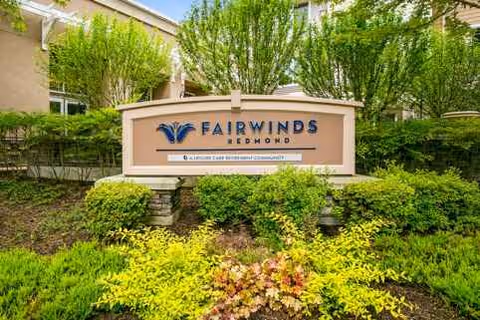 Sign for Fairwinds Redmond surrounded by lush landscaping at the property entrance.