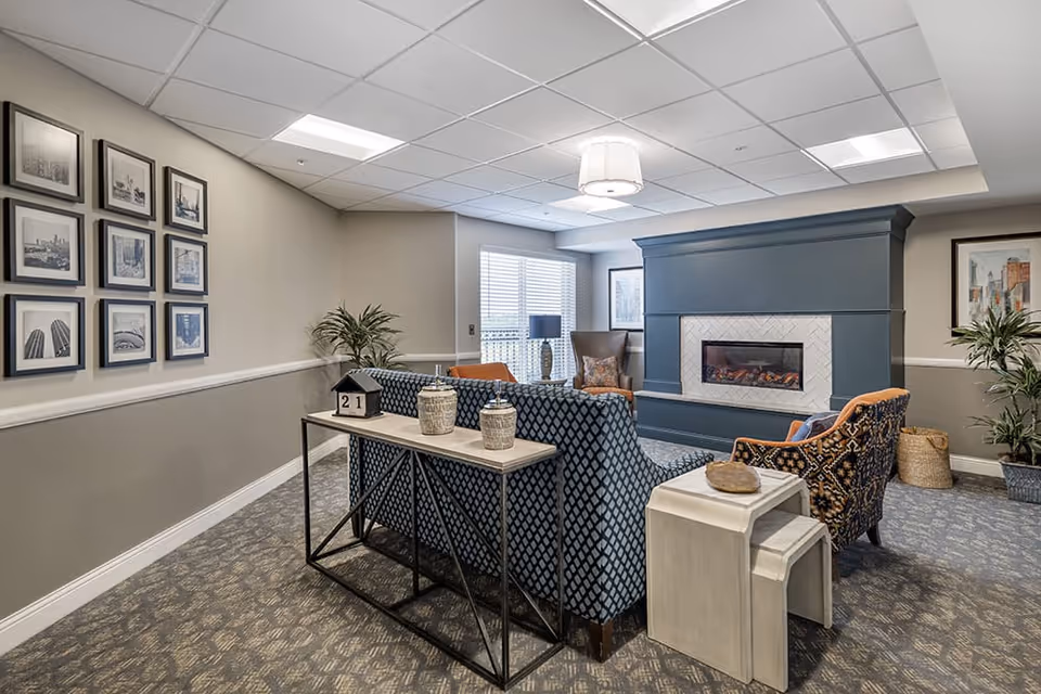 Comfortable communal lounge with sofas and armchairs arranged around a fireplace and a console table.
