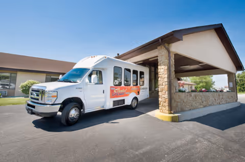 A white shuttle bus parked at the front entrance of Wesleyan Health and Rehabilitation Center.