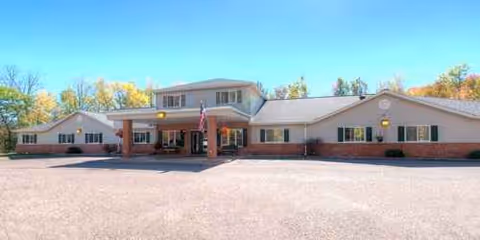 Long single-story senior living facility with brick facade, entrance, and a wide parking lot.
