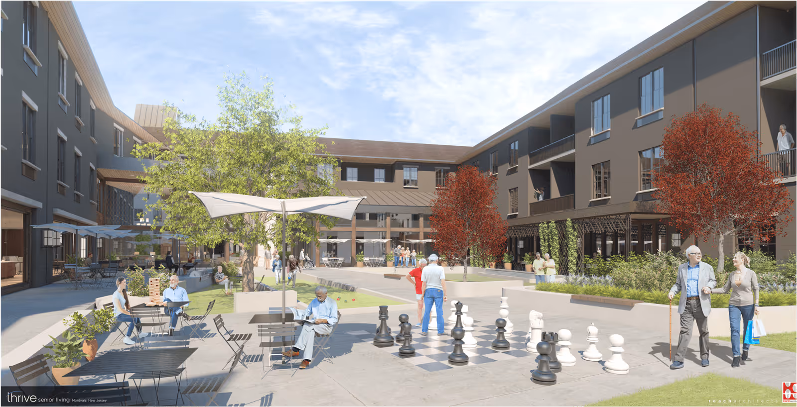 Outdoor courtyard area of a senior living facility with people engaging in various activities including playing giant chess, reading, and socializing. The courtyard is surrounded by a multi-story building with balconies, trees with green and red leaves, tables with umbrellas, and potted plants under a clear blue sky.