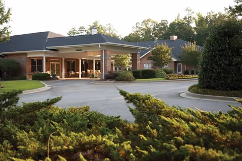 Exterior view of a senior living facility with a covered entrance and landscaped grounds.