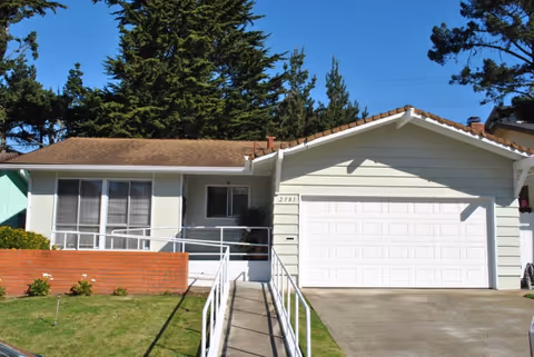 A single-story care home exterior with a white garage and front ramp.