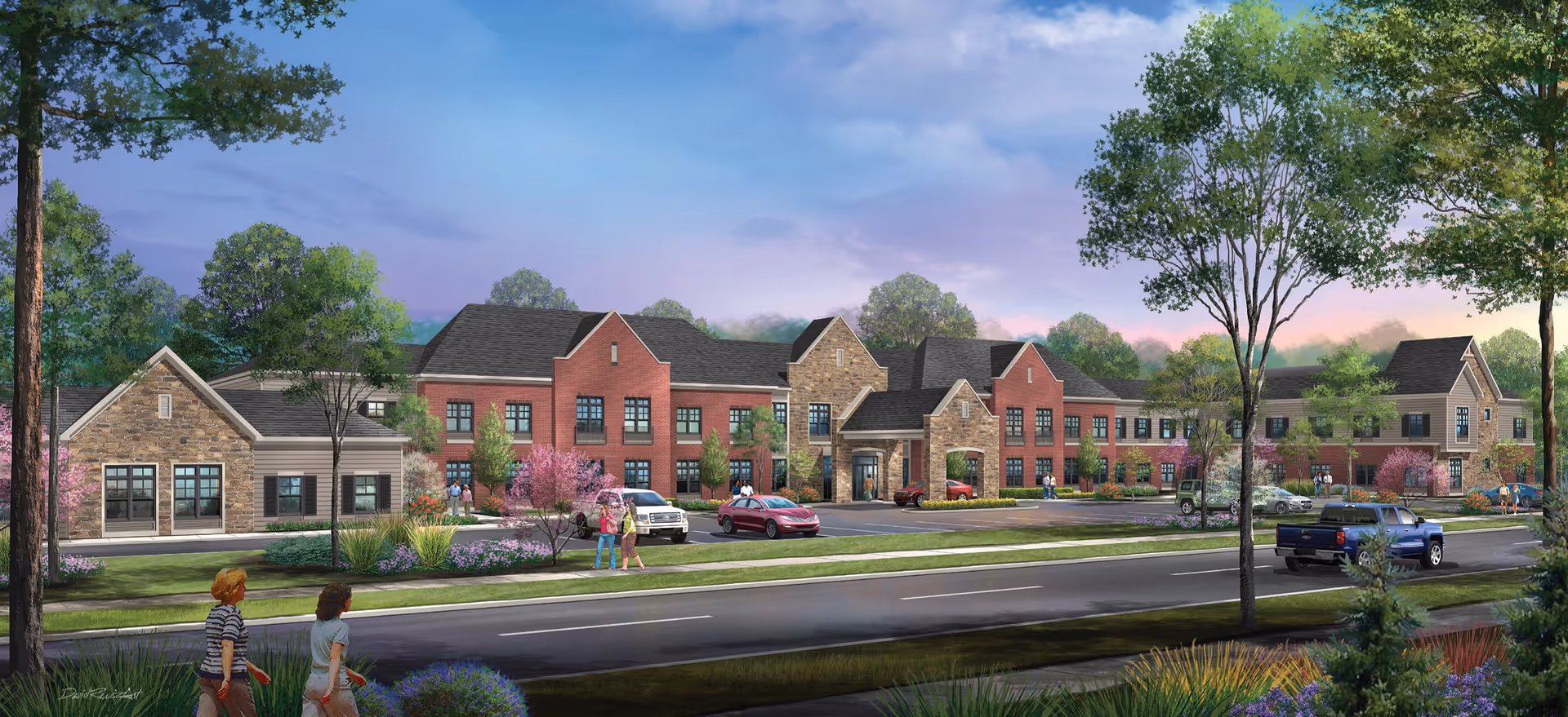 Exterior view of Oakleigh of Macomb Senior Living facility showing a large two-story building with brick and stone facade, surrounded by trees, landscaped gardens, and a parking area with several cars. People are walking on the sidewalk in front of the building under a partly cloudy sky at dusk.
