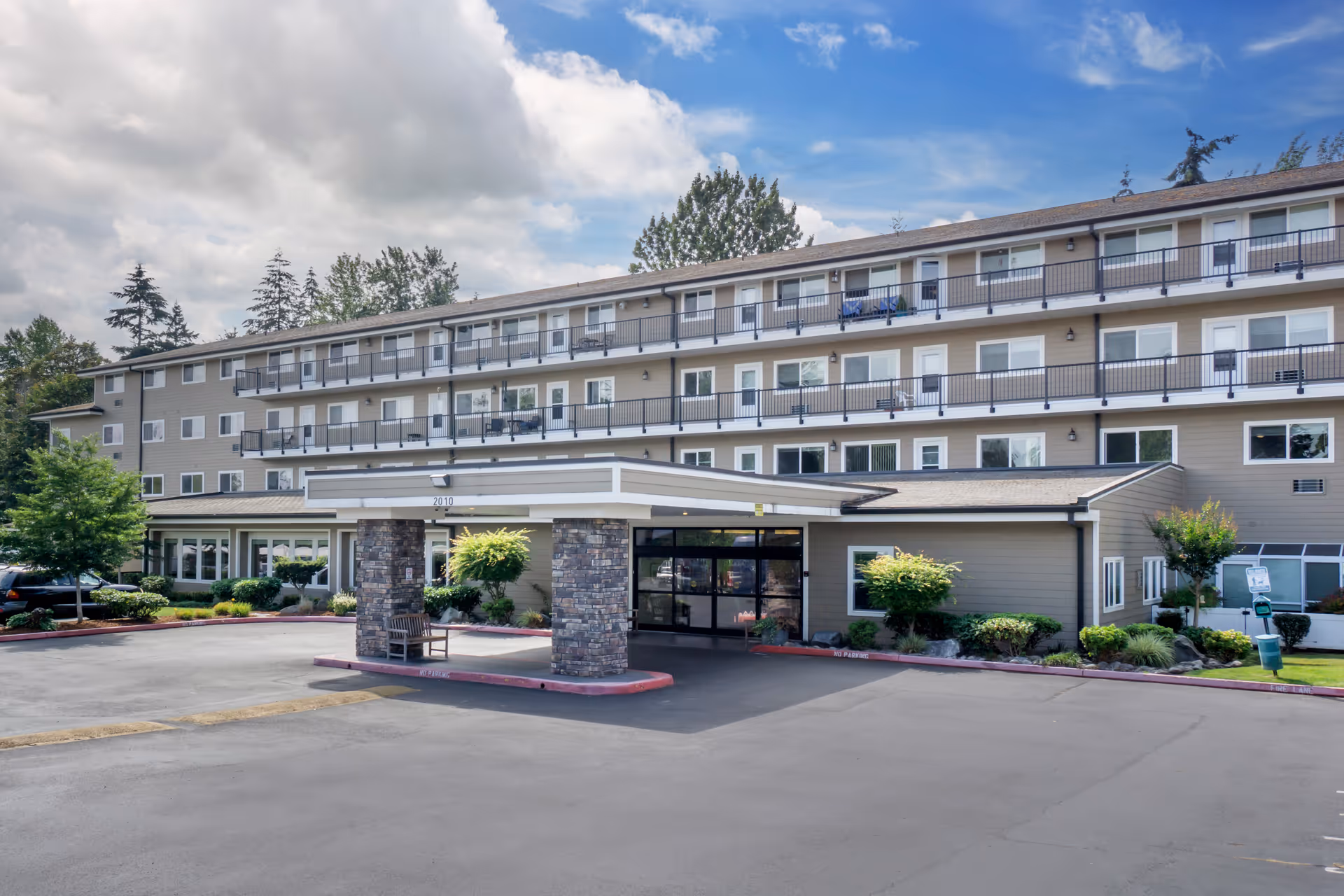 Three-story Brookdale Allenmore independent living building with glass entry and surrounding parking lot.
