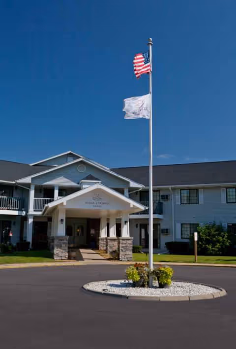 Exterior view of Baldwin House Senior Living Lansing entrance with flagpole and American flag.