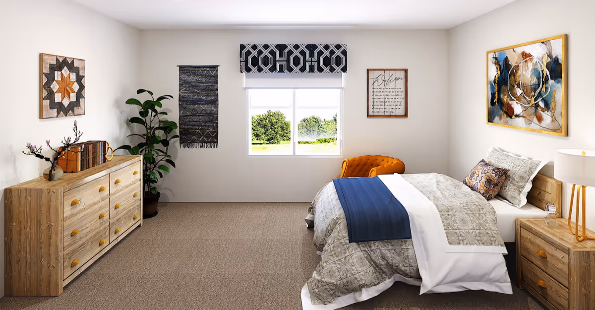 Furnished bedroom with a bed, wooden dresser and nightstand, an orange chair, wall art, and a window showing greenery.