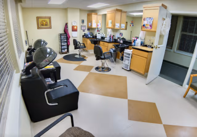 Interior salon with styling chairs, hooded hair dryers, wash sinks and cabinetry.