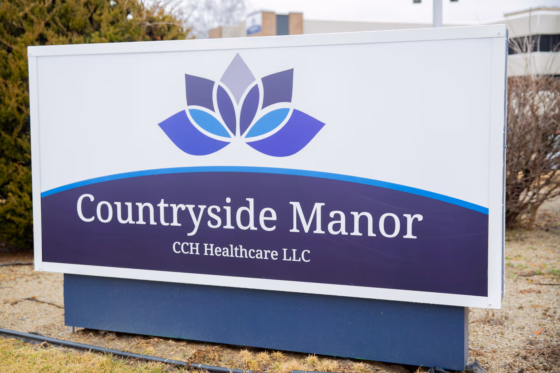 Outdoor sign for Countryside Manor CCH Healthcare LLC with a blue and purple lotus flower logo above the text.