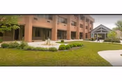 Exterior view of a brick senior living facility with manicured lawn and walkway.