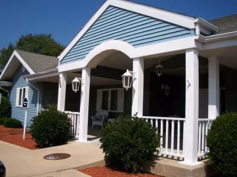 Blue exterior building with a white porch, columns, and hanging lantern lights.