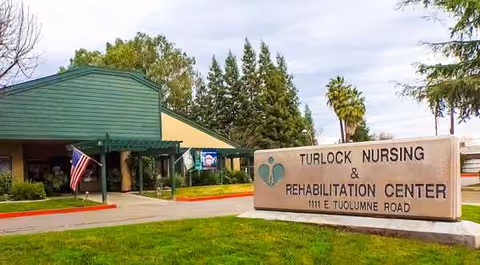 Exterior view of Turlock Nursing and Rehabilitation Center with a large sign at the entrance.