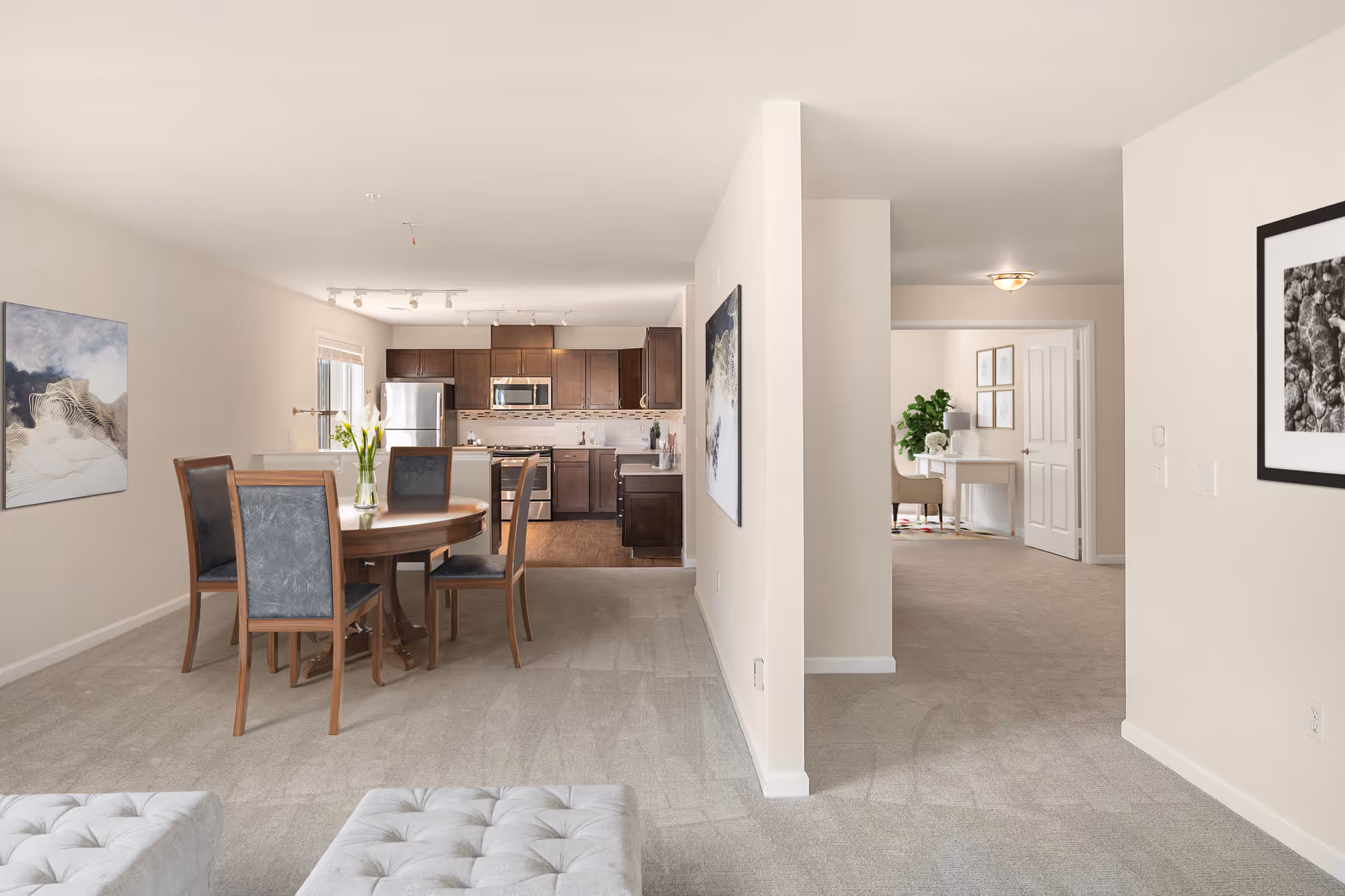 Open-plan interior showing a dining table and chairs in front of a modern kitchen with a hallway leading to additional rooms.