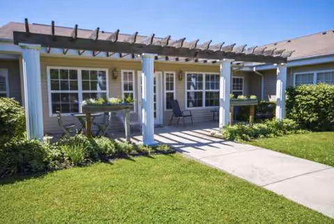 Exterior view of a single-story facility with a covered porch, seating, and a lawn.