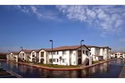 Exterior view of The Jasmine at Founders Village, a white senior living building along a canal.