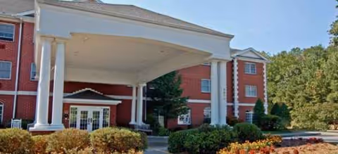 Brookdale Durham brick senior living building with tall white columns, a covered entrance, and shrubs.