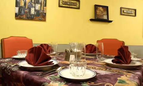 A dining table set with plates, glasses, and folded napkins in a colorful dining room.