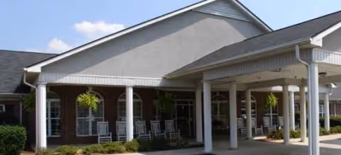 Exterior view of Brookdale Robinwood entrance with a covered front porch and rocking chairs.