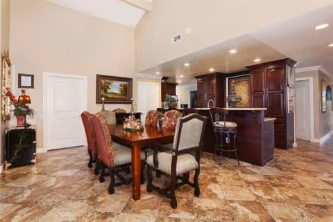 Verona Court II dining room with a long wooden table, upholstered chairs, and a bar area.