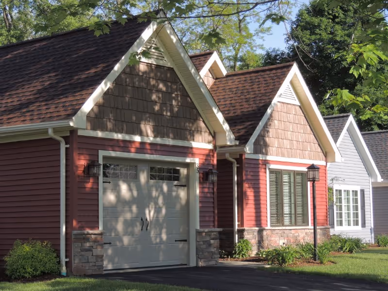 Cottage-style townhomes with garages line a tree-shaded lawn.