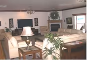 Spacious living room with beige sofas arranged around a coffee table, a TV, and a fireplace.
