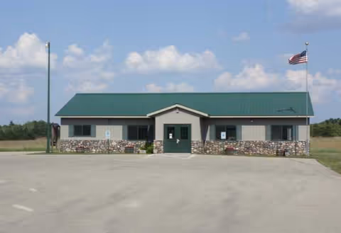 Evergreen Terrace facility front view with green metal roof, stone base, and flagpole near parking.