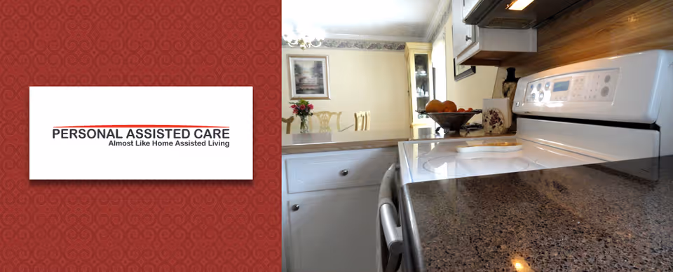 A kitchen area with a white electric stove and oven, granite countertops, white cabinets, and a dining area visible in the background with a table, chairs, and a vase of flowers.
