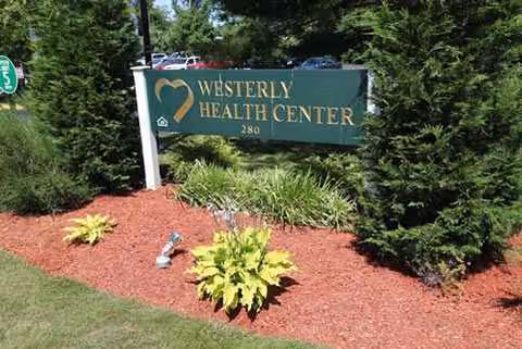 Outdoor sign for Westerly Health Center surrounded by red mulch and plants.