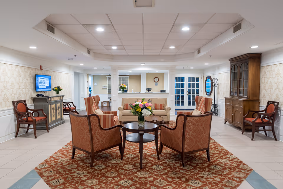 Reception lobby with upholstered chairs and a sofa arranged around a coffee table with a floral centerpiece.