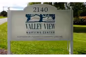 Outdoor sign for Valley View Nursing Center with the address number 2140 displayed above the facility name. The sign is white with blue text and graphics, situated on a grassy area near a road.