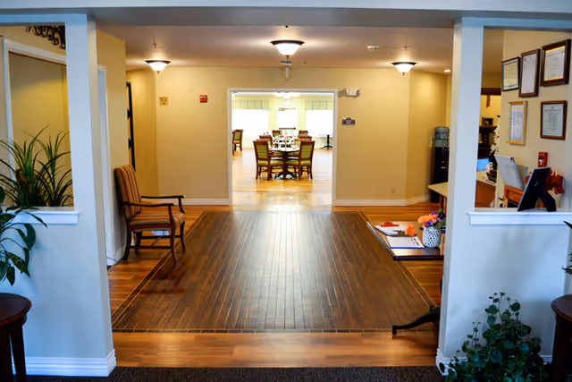 Entry hallway and common area leading to a dining area with a round table and chairs.