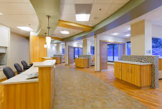 Spacious modern reception lobby with curved ceiling accents, wooden reception desks, and seating near large windows.
