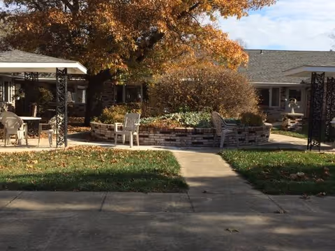 Outdoor courtyard of Clearview Estates Assisted Living with stone planter, trees, and seating.