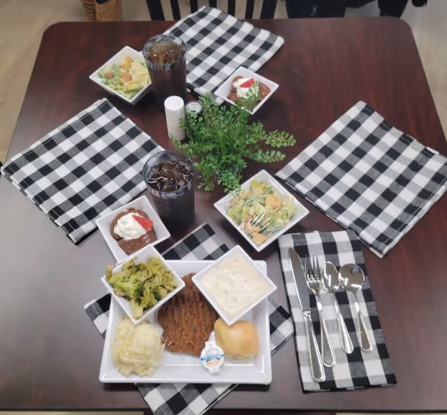 Dining table set for a meal with checkered napkins and drinks.