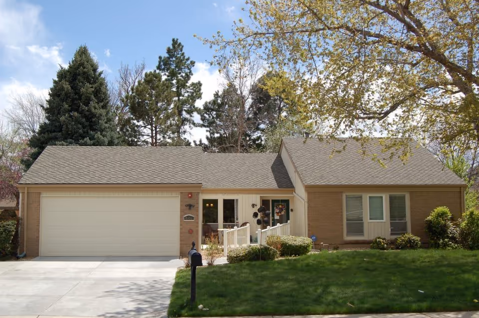 Single-story brick house-style building with attached two-car garage and front yard.