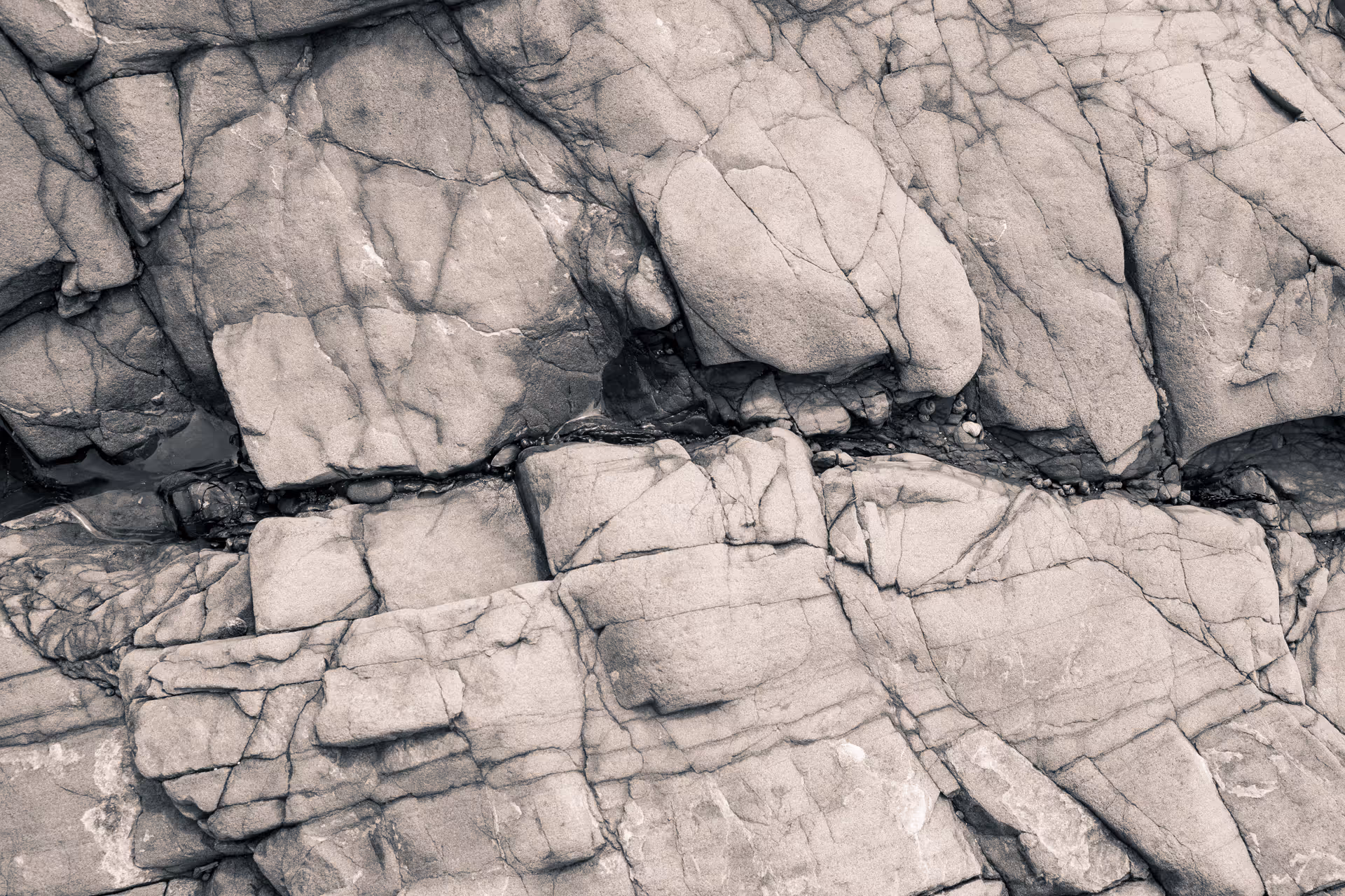 Close-up of layered, cracked gray rock formations with visible fissures and textured surfaces.