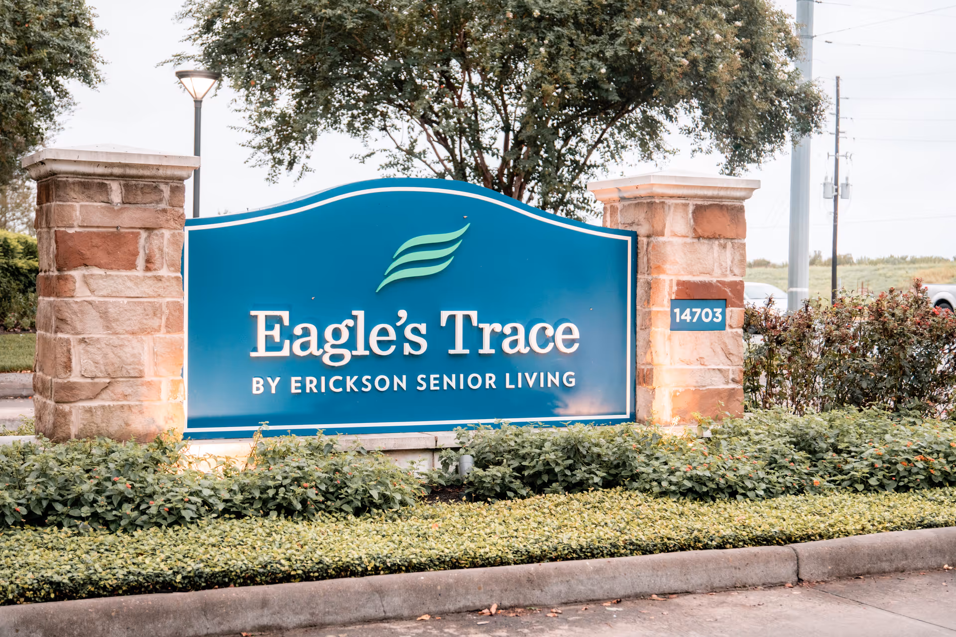 Entrance sign reading "Eagle's Trace by Erickson Senior Living" mounted between stone pillars with landscaping in front.