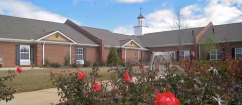Exterior view of Ashlan Village building with rose bushes and clear blue sky.