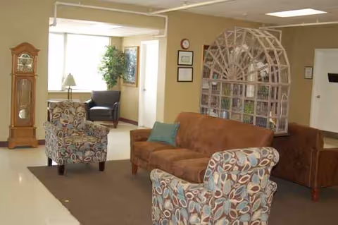 Ackert Park senior living lounge with patterned chairs, sofa, grandfather clock, and decorative divider.