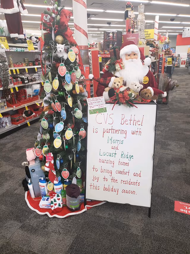 Christmas display inside a CVS store showing a decorated tree, a Santa figure and a whiteboard sign announcing CVS Bethel's partnership with Morris and Locust Ridge nursing homes.