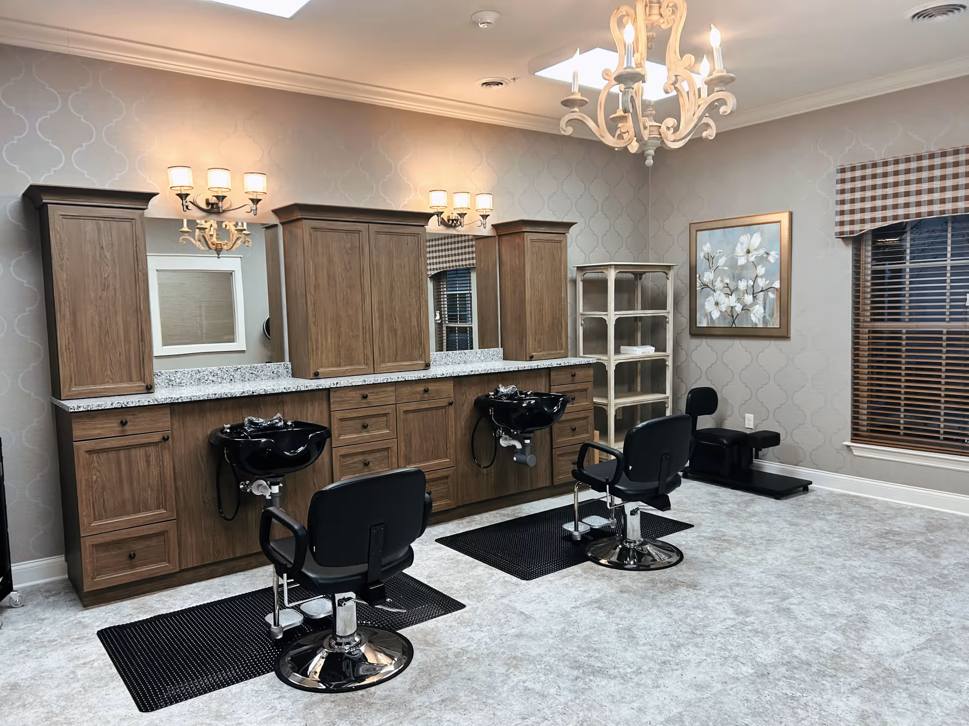 Bright salon-style hairdressing area with two styling chairs, shampoo sinks, wooden cabinets, and decorative lighting.