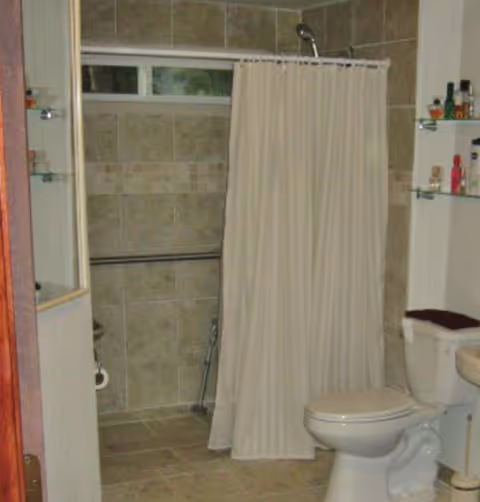 A bathroom with a white shower curtain, toilet, and tiled walls.